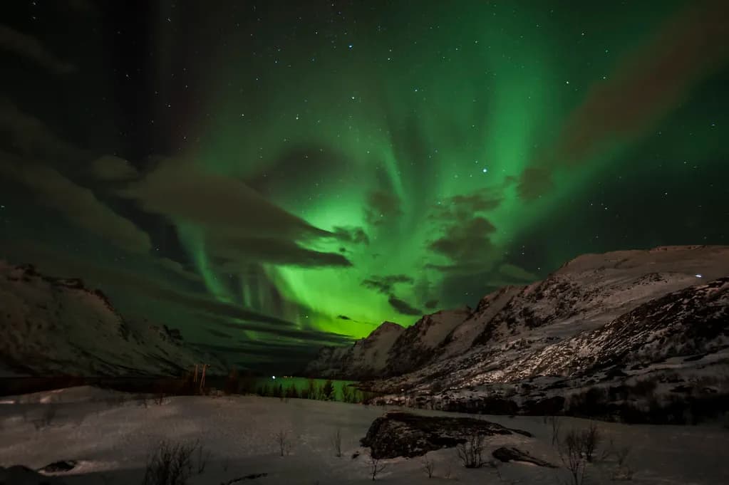 aurore boréale au-dessus d'une vallée enneigée lors d'une sortie nocturne près de Tromsø