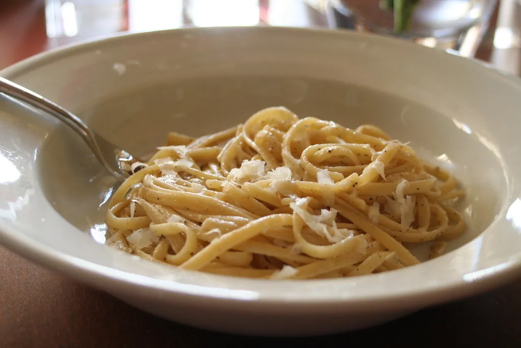 a bowl of tonnarelli cacio e pepe sprinkled with grated cheese