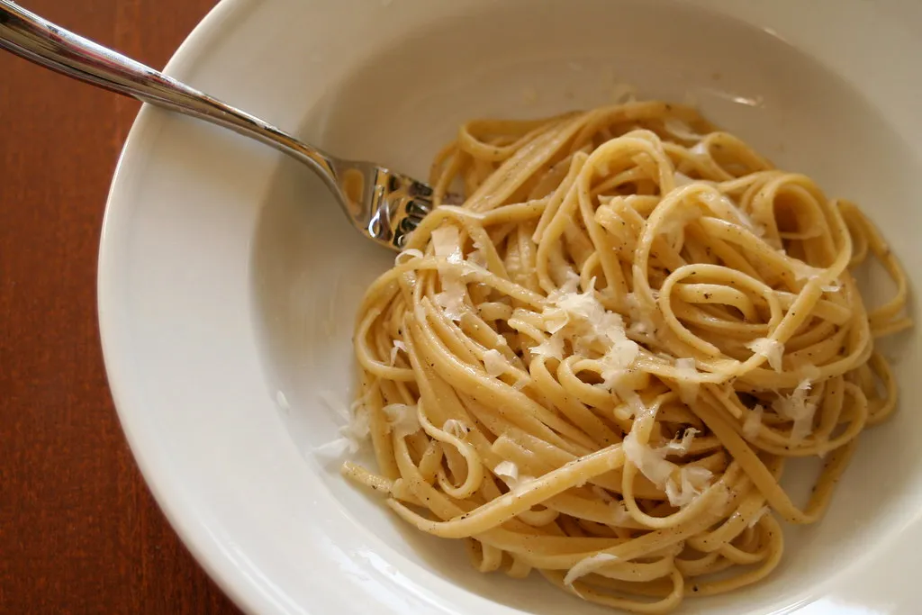 a plate of cacio e pepe pasta with pecorino and black pepper