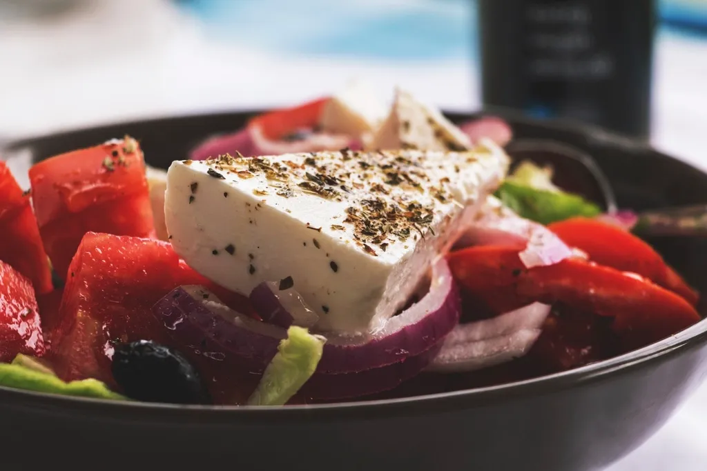 Greek salad topped with a slab of feta, tomatoes and red onion