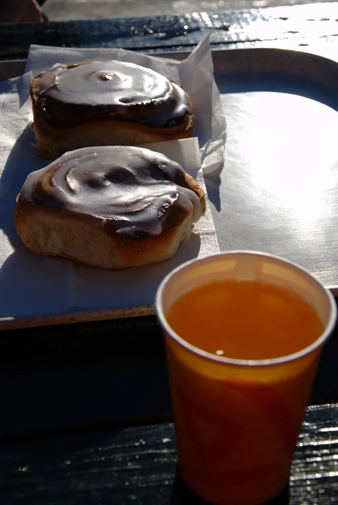 brioche à la cannelle glacée au chocolat accompagnée d'une boisson chaude