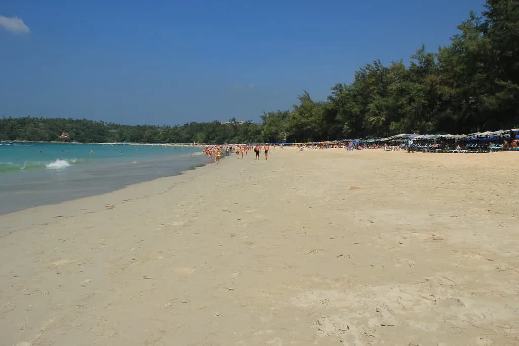 la grande étendue de sable de Kamala Beach sous un ciel bleu, avec quelques promeneurs