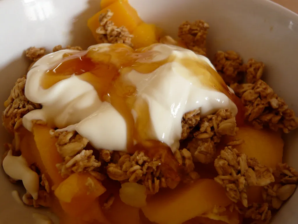 yogurt drizzled with honey over granola and fruit for breakfast
