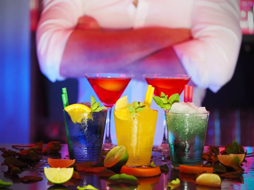 colourful cocktails garnished with fruit lined up on a bar counter