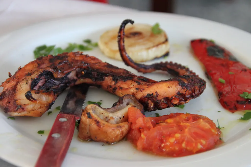 charcoal-grilled octopus served with pepper and tomato in a Greek taverna