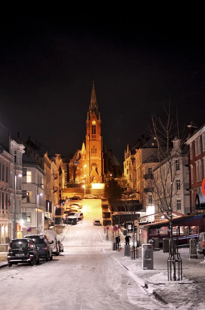 rue de Bergen enneigée la nuit, montant vers une grande église en brique illuminée