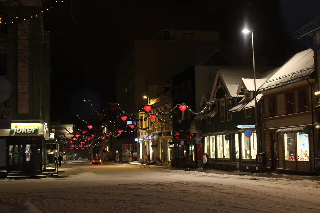 rue enneigée de Tromsø la nuit, décorée de cœurs lumineux pour Noël