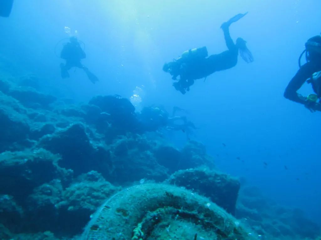 divers exploring a rocky seabed in the clear waters of Greece