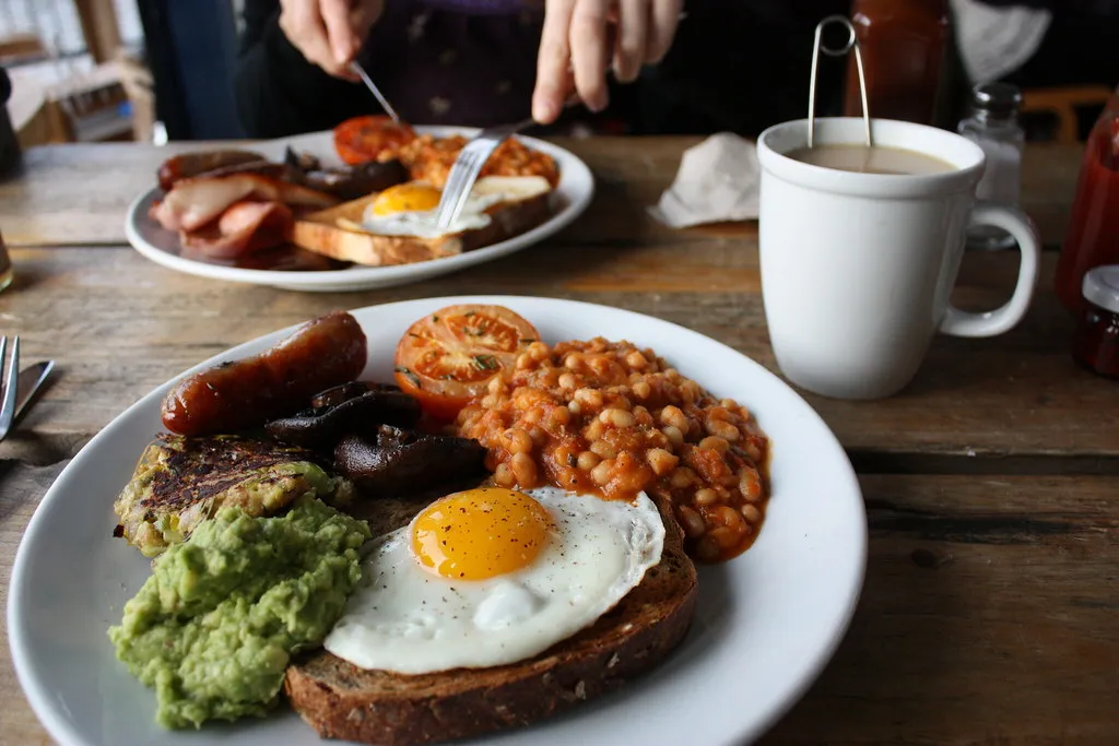 a hearty breakfast with fried egg, sausages, beans and avocado