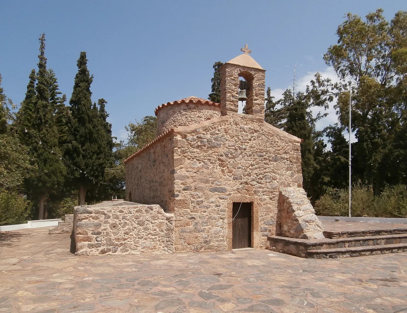 La chapelle byzantine d'Agios Nikolaos en pierre, avec son clocher, entourée de cyprès