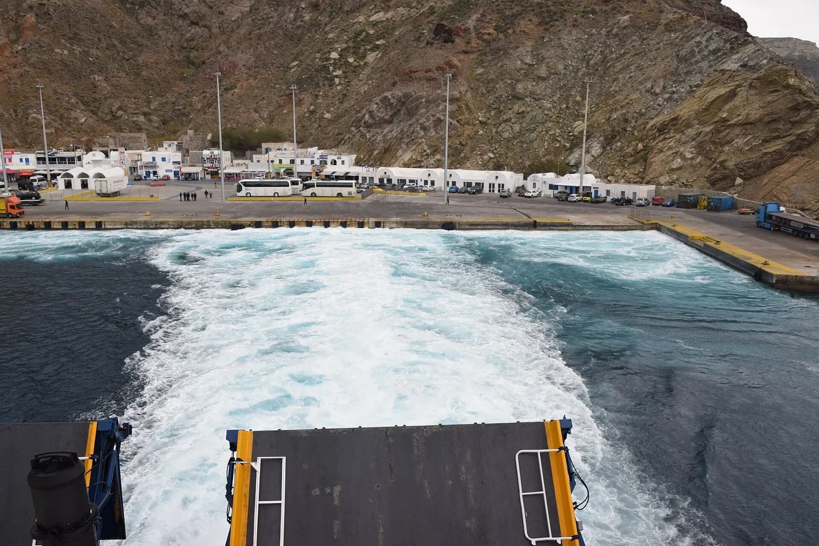 Le sillage blanc d'un ferry qui quitte le port d'Athinios, sous les falaises de Santorin