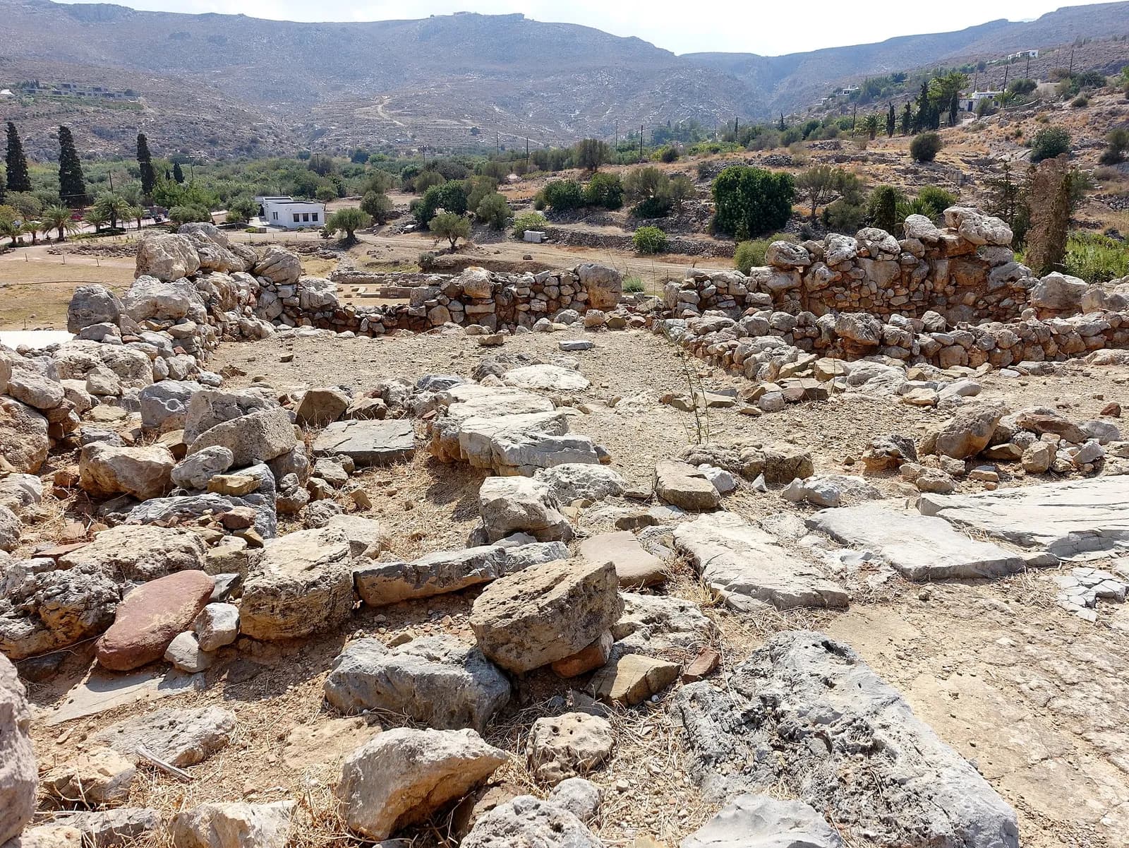 Murs et dallages du palais minoen de Zakros, avec la vallée et les collines en arrière plan