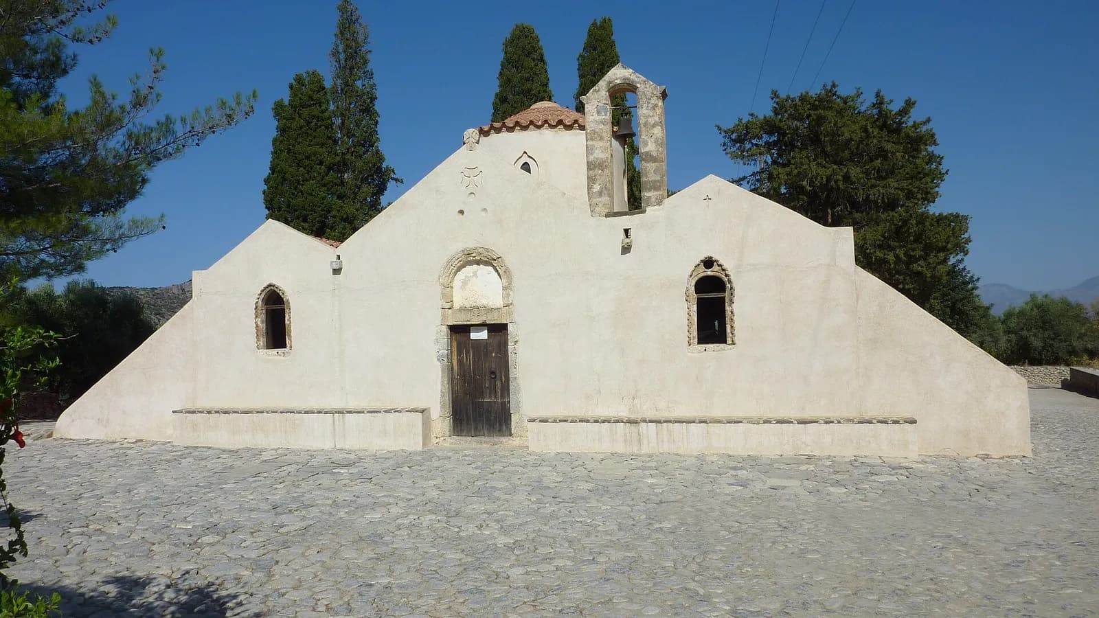 L'église Panagia Kera de Kritsa, sa façade blanche à contreforts et son clocher entourés de cyprès