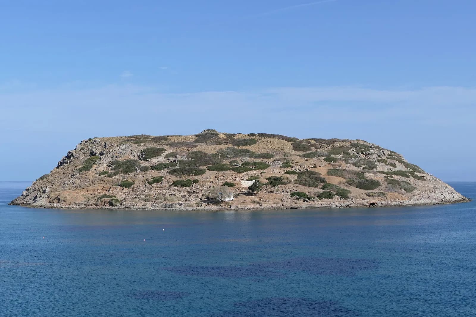 L'îlot rocheux de Mochlos, site minoen, posé sur la mer bleue face au village de Mochlos