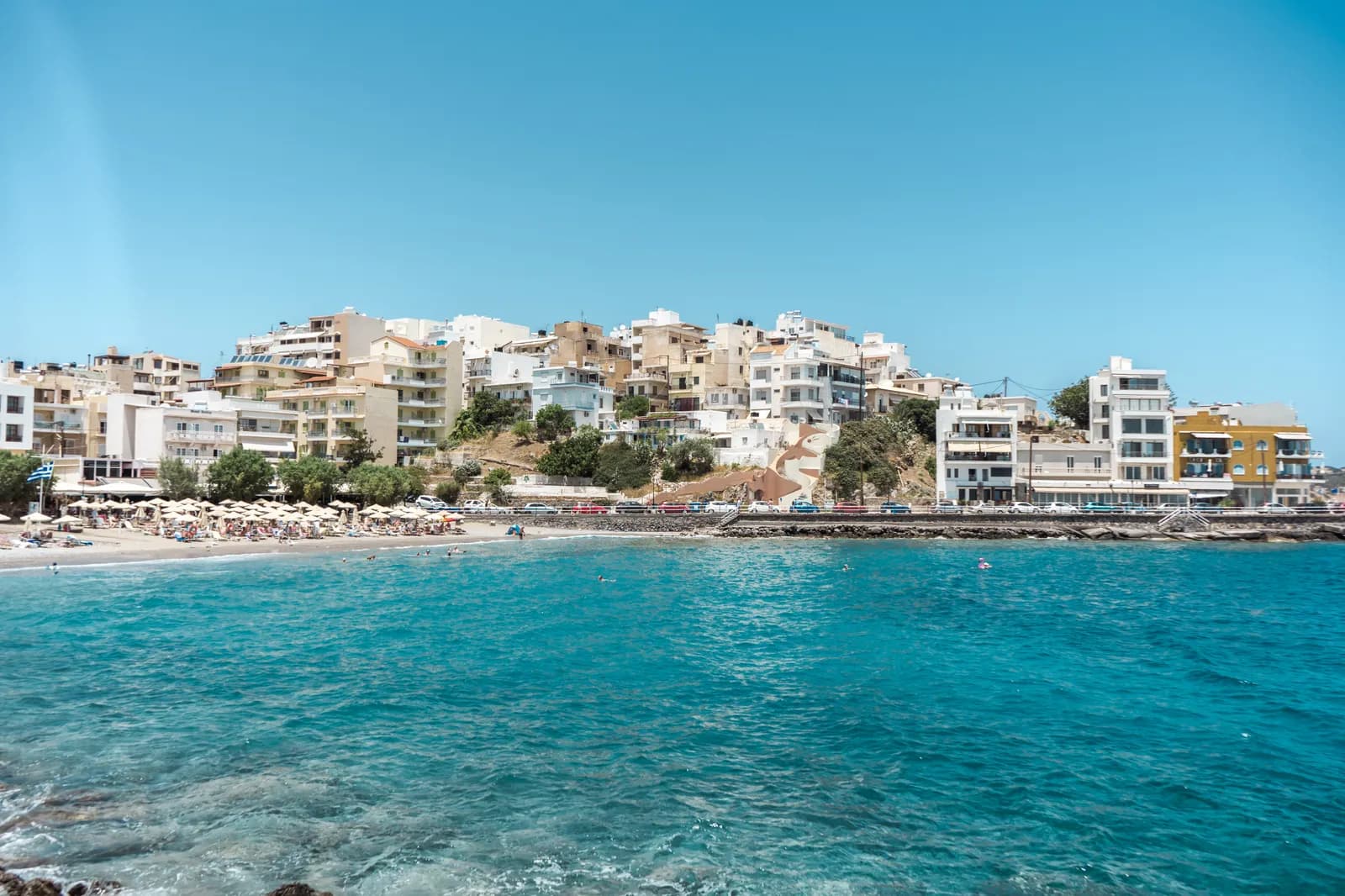 La plage de Kitroplatia et ses parasols au pied des immeubles d'Agios Nikolaos, face à une mer turquoise