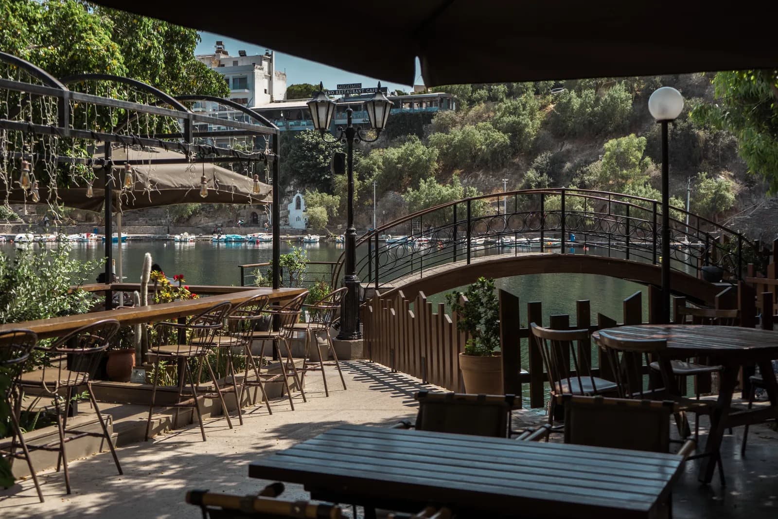 Terrasse de café ombragée au bord du lac Voulismeni, près de la passerelle en fer forgé