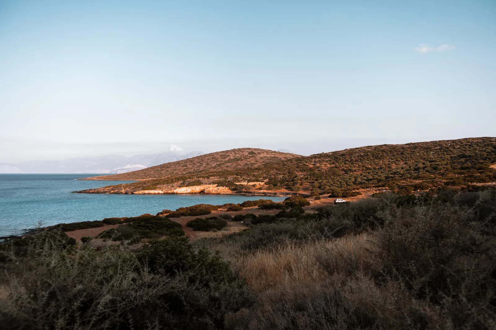 Presqu'île couverte de garrigue dorée par la lumière du soir au bord du golfe d'Elounda