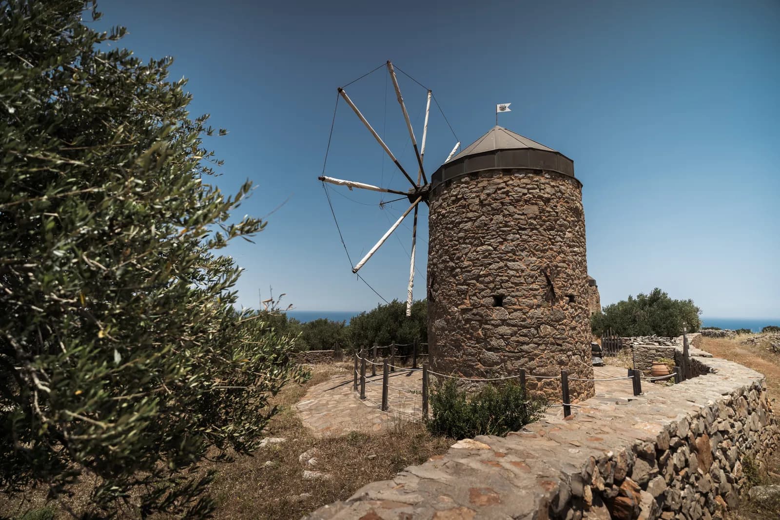 Moulin à vent de pierre et ses ailes en bois au milieu des oliviers, sur le plateau au nord de Plaka