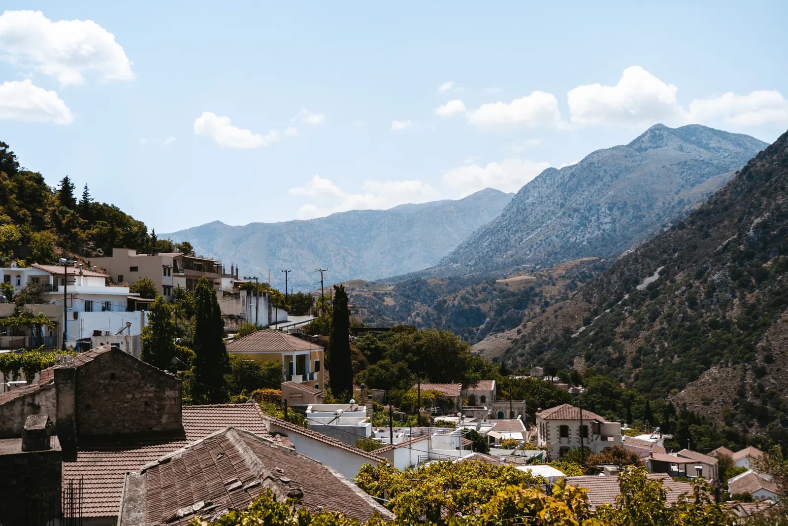 Le village d'Argyroupoli accroché à la colline, sous les sommets et les nuages des montagnes de l'ouest