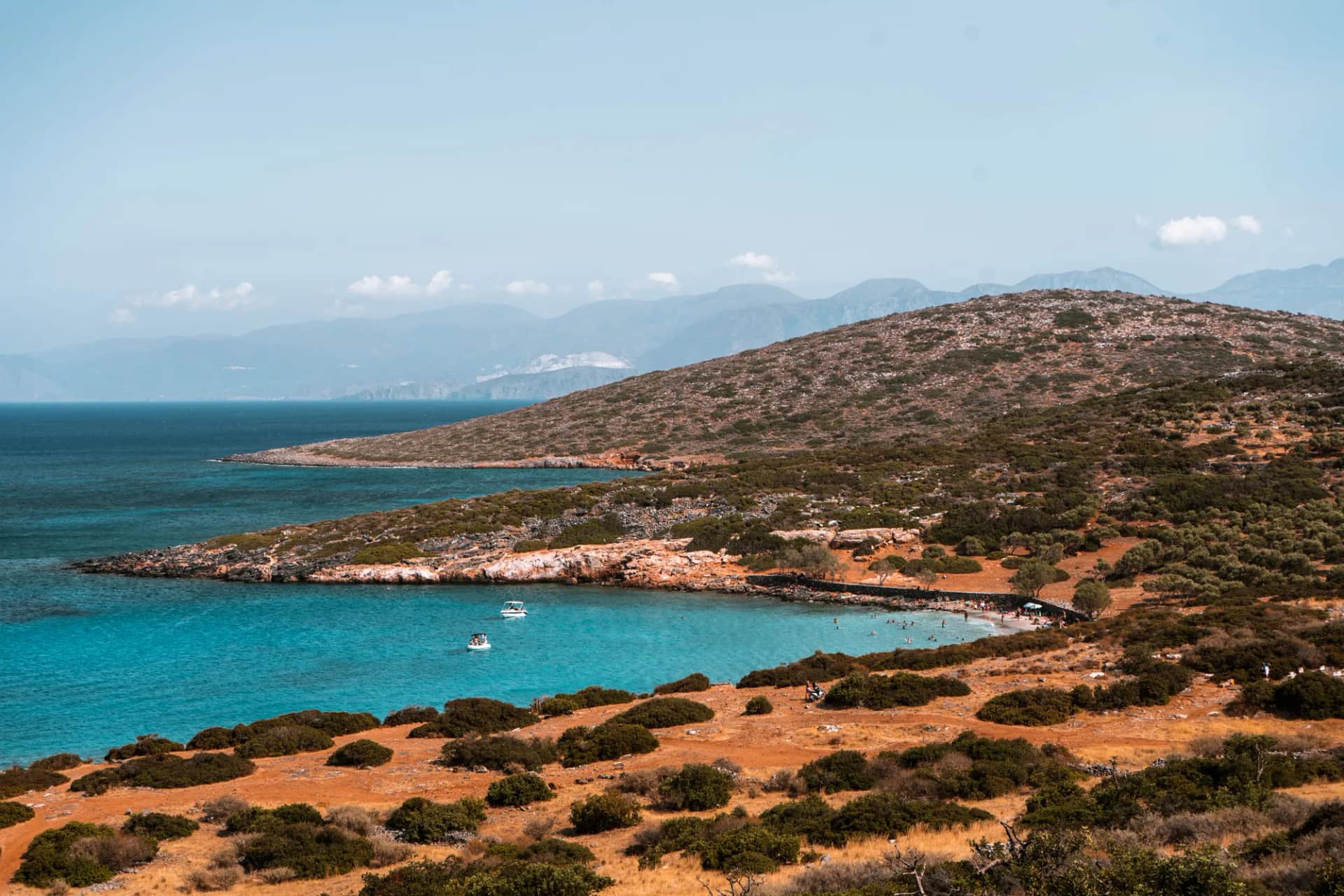 Turquoise cove and scrub-covered hills near Elounda, facing the mountains of eastern Crete in summer
