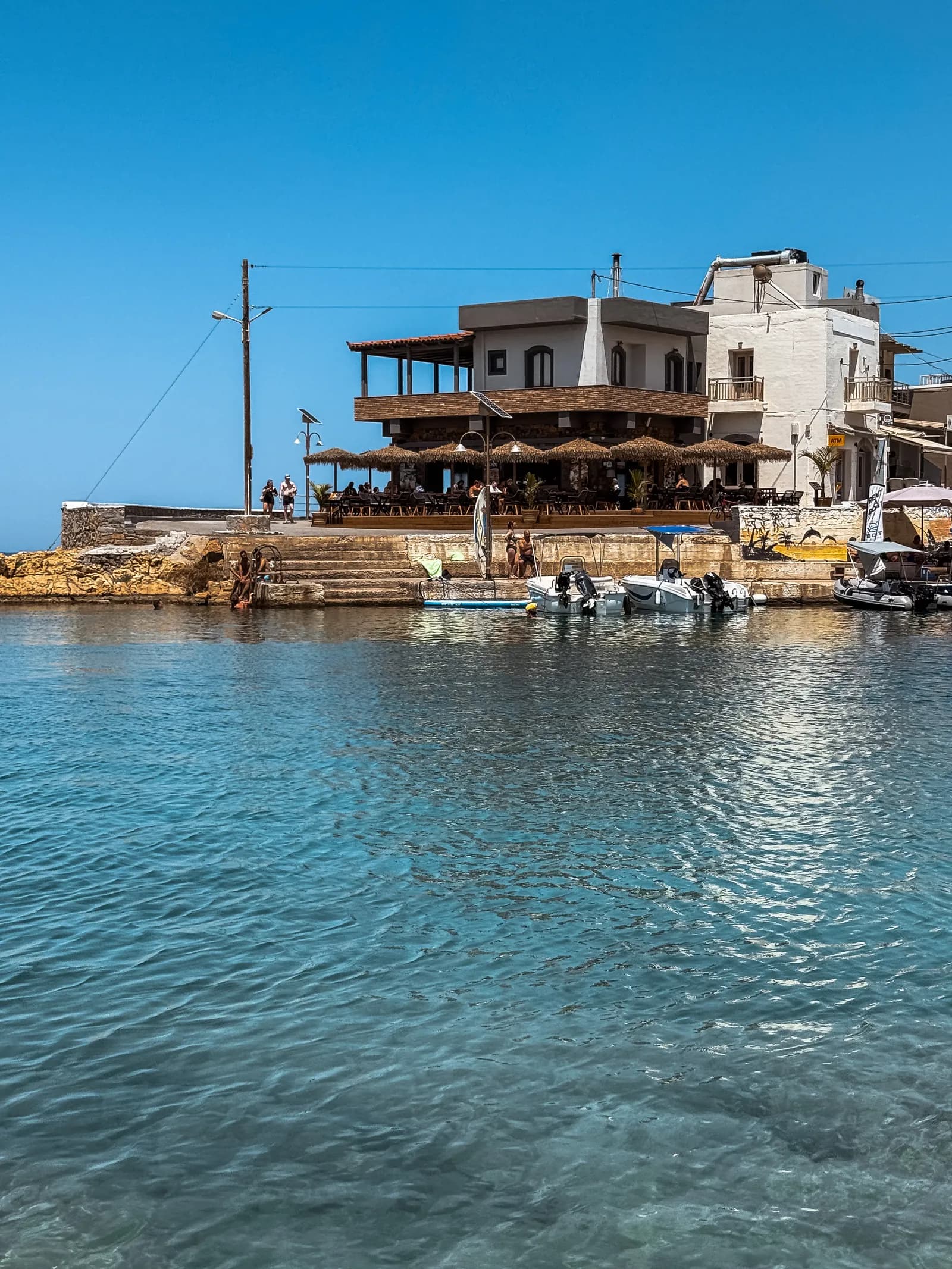 Taverne à étage dominant l'eau transparente du port de Sisi, sur la côte nord