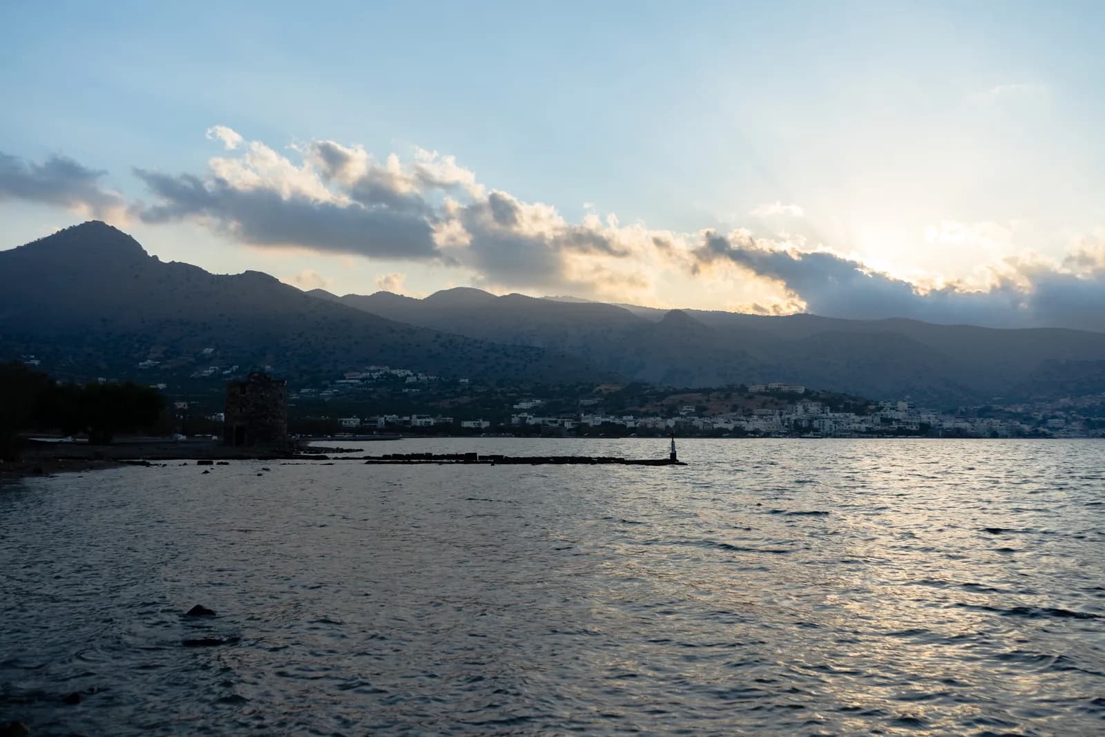 Nuages et lumière de fin de jour sur le golfe d'Elounda, avec un vieux moulin au bord de l'eau