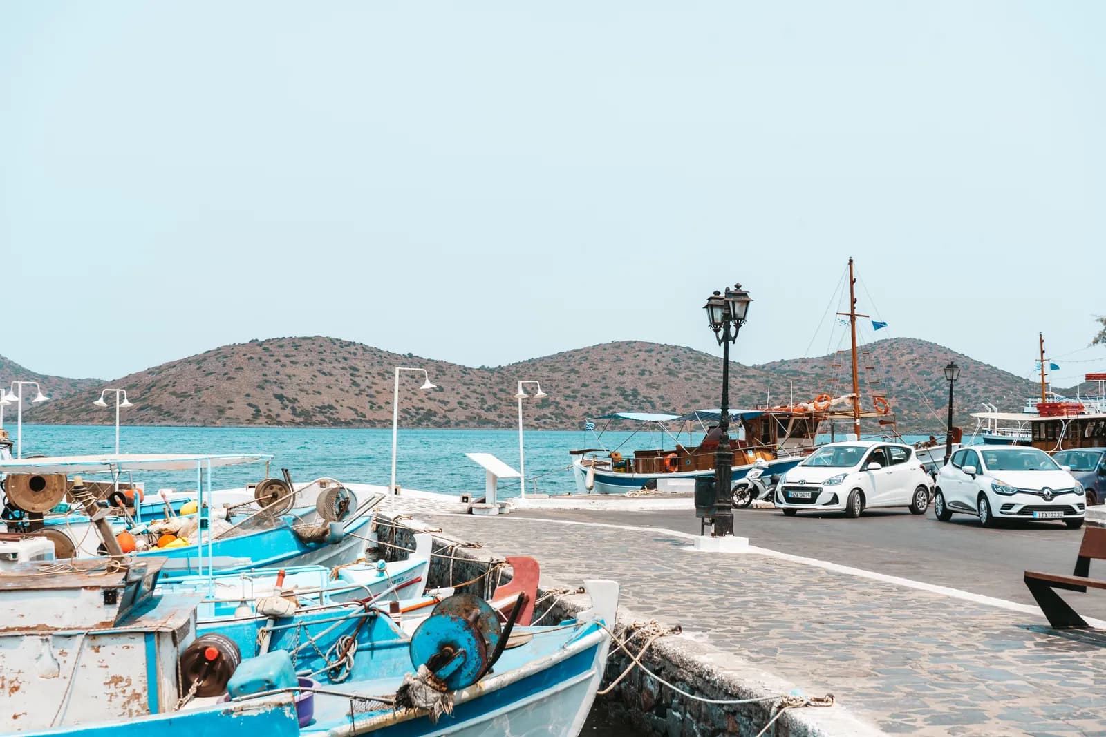 Barques de pêche bleues et caïques amarrés au port de Schisma, sur le quai d'Elounda face aux collines