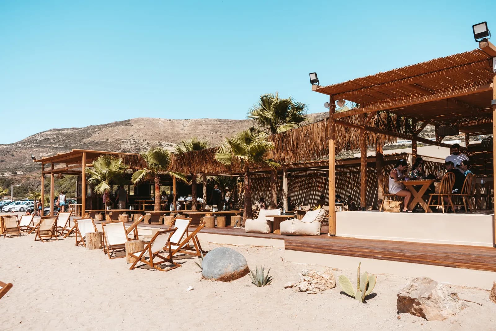 Wooden beach bar and sun loungers under the palm trees, on the sand at Falassarna