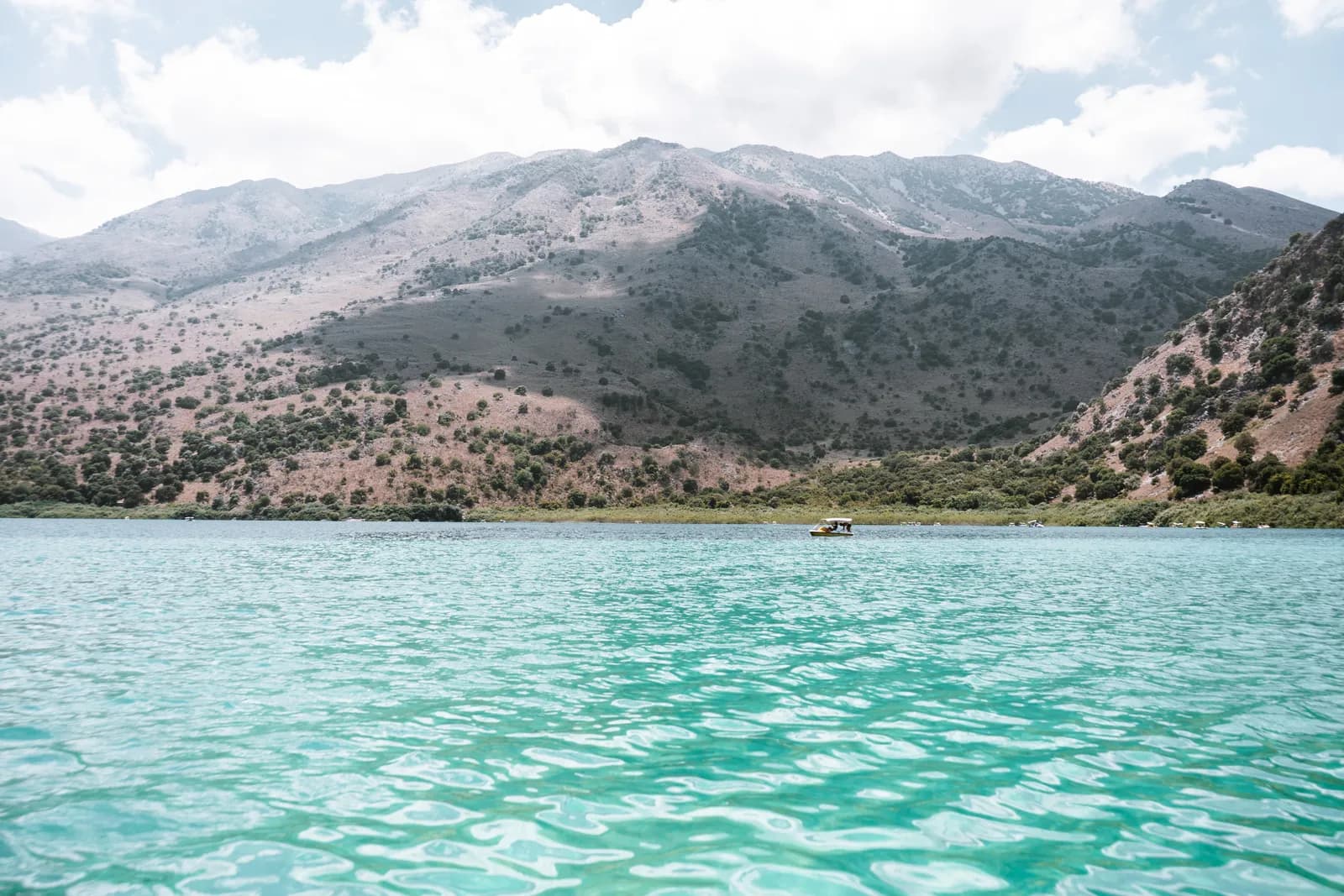 Eau turquoise du lac Kournas en été, sous les montagnes et un ciel nuageux