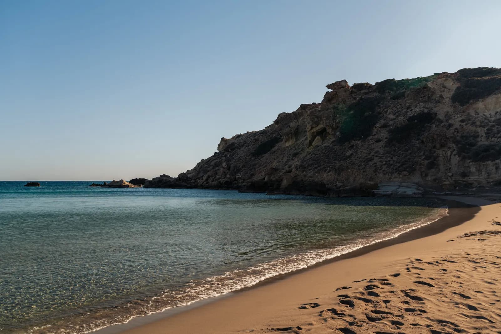 Crique de sable fin et d'eau claire au pied d'une falaise sur la côte sud-est de la Crète, près d'Ierapetra