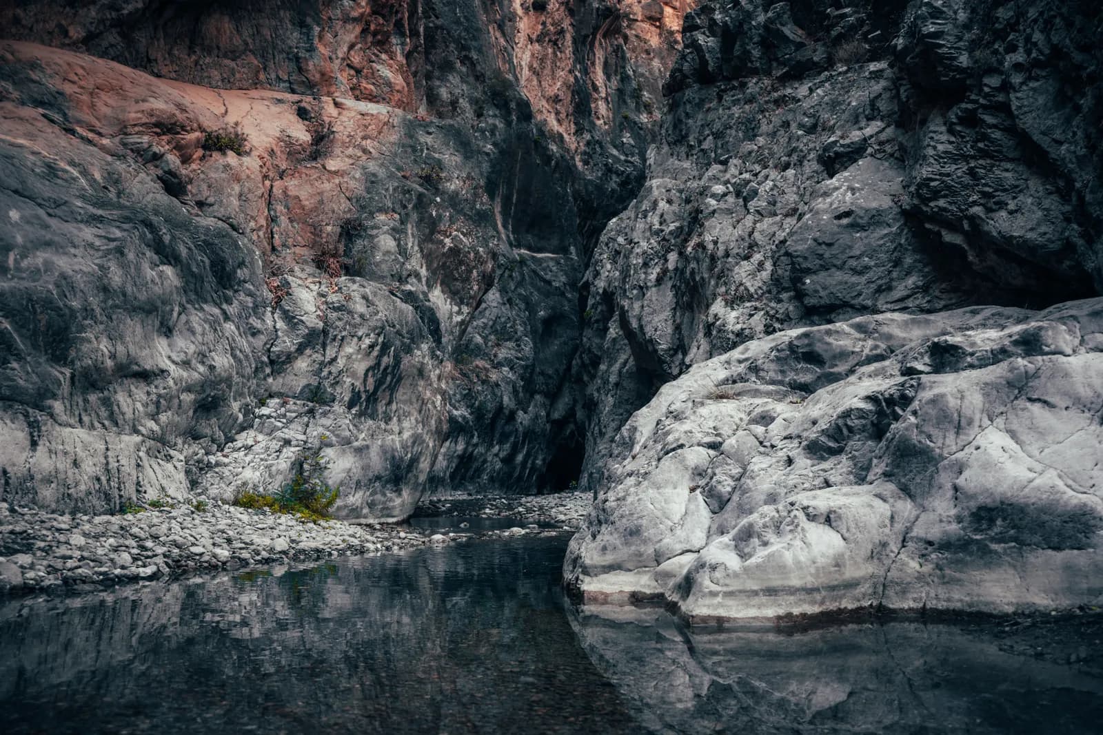 Parois sculptées et rochers polis se reflétant dans un bassin d'eau calme au fond de la gorge de Sarakina