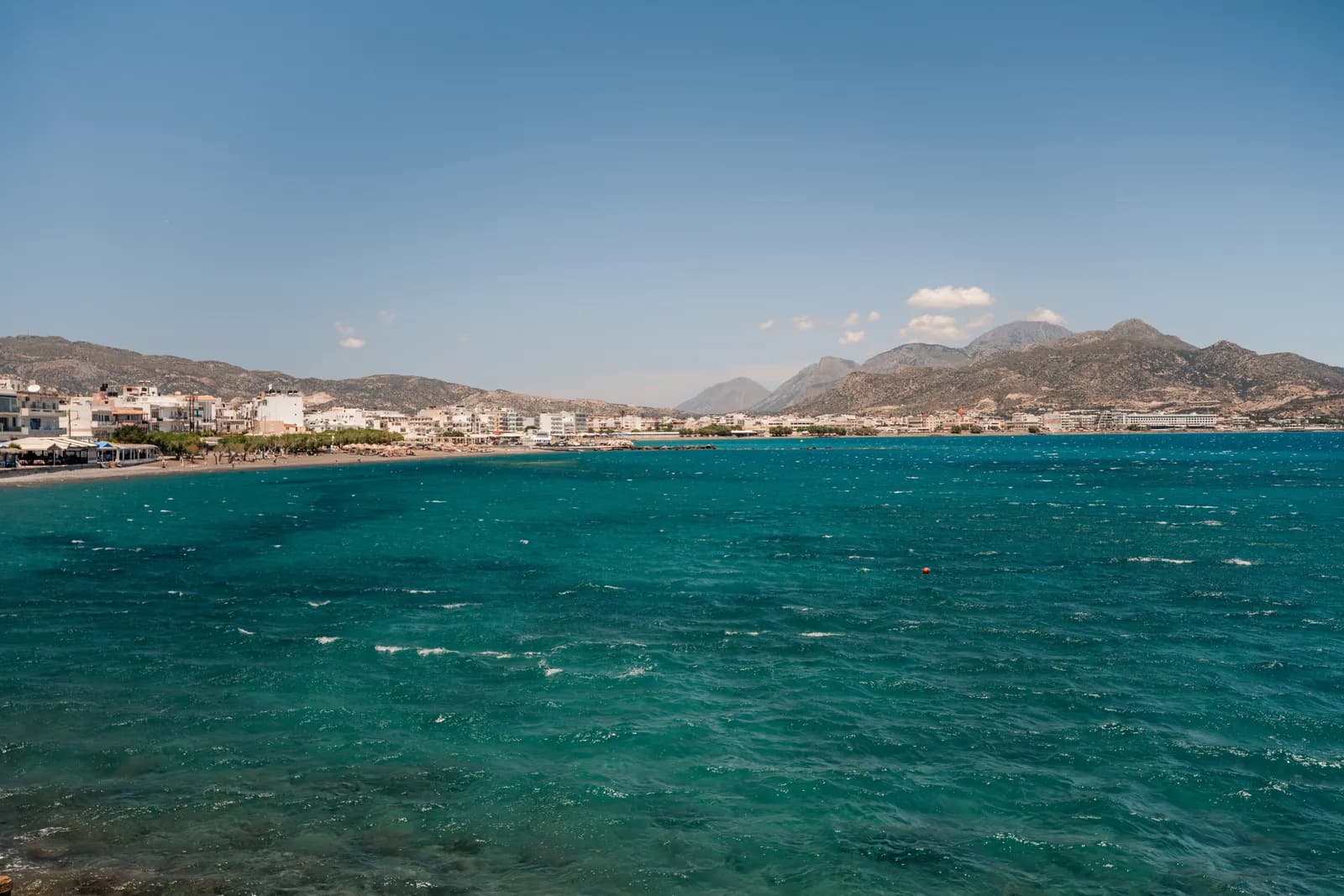 Mer turquoise agitée par le vent devant la ville d'Ierapetra et ses montagnes, sous un grand soleil