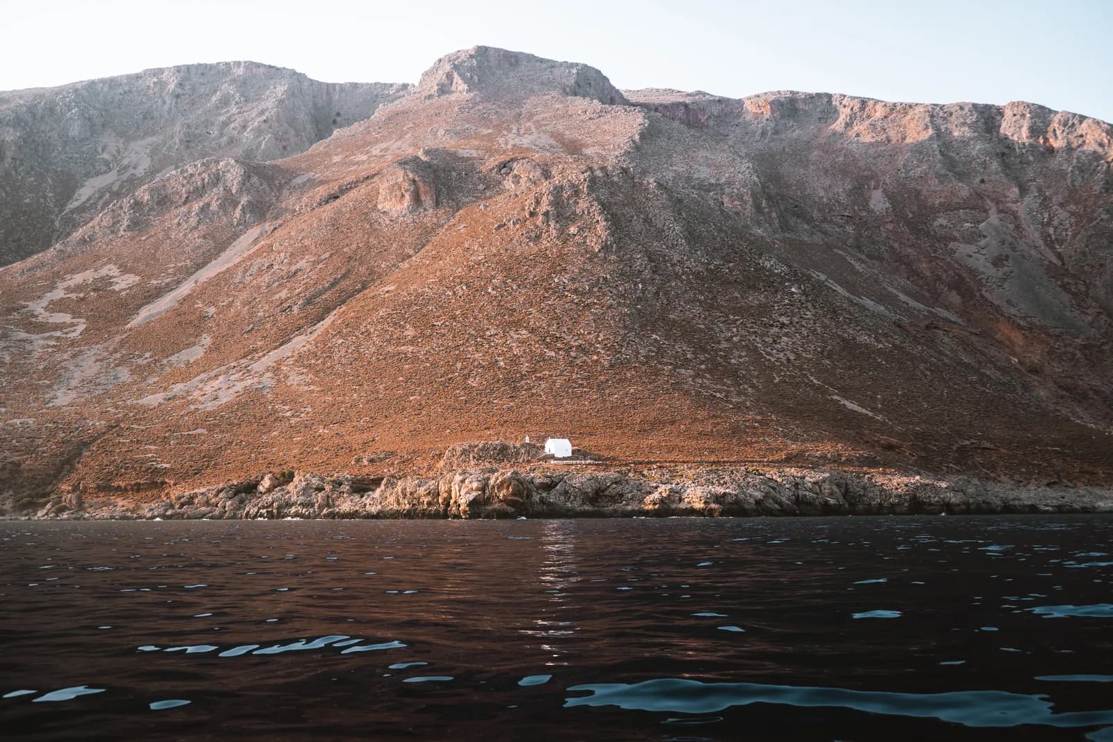 Lonely white chapel at the foot of the Sfakia mountains, seen from a boat in the evening light