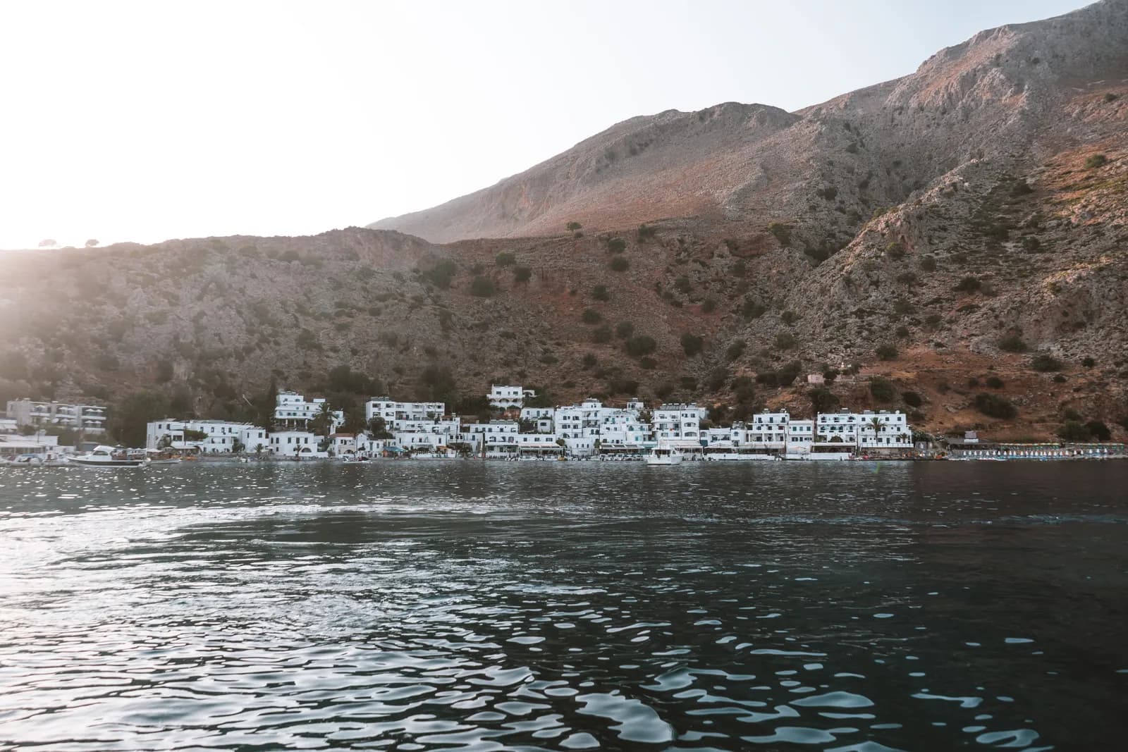 The white houses of Loutro seen from the sea, at the foot of the Sfakia mountains late in the day
