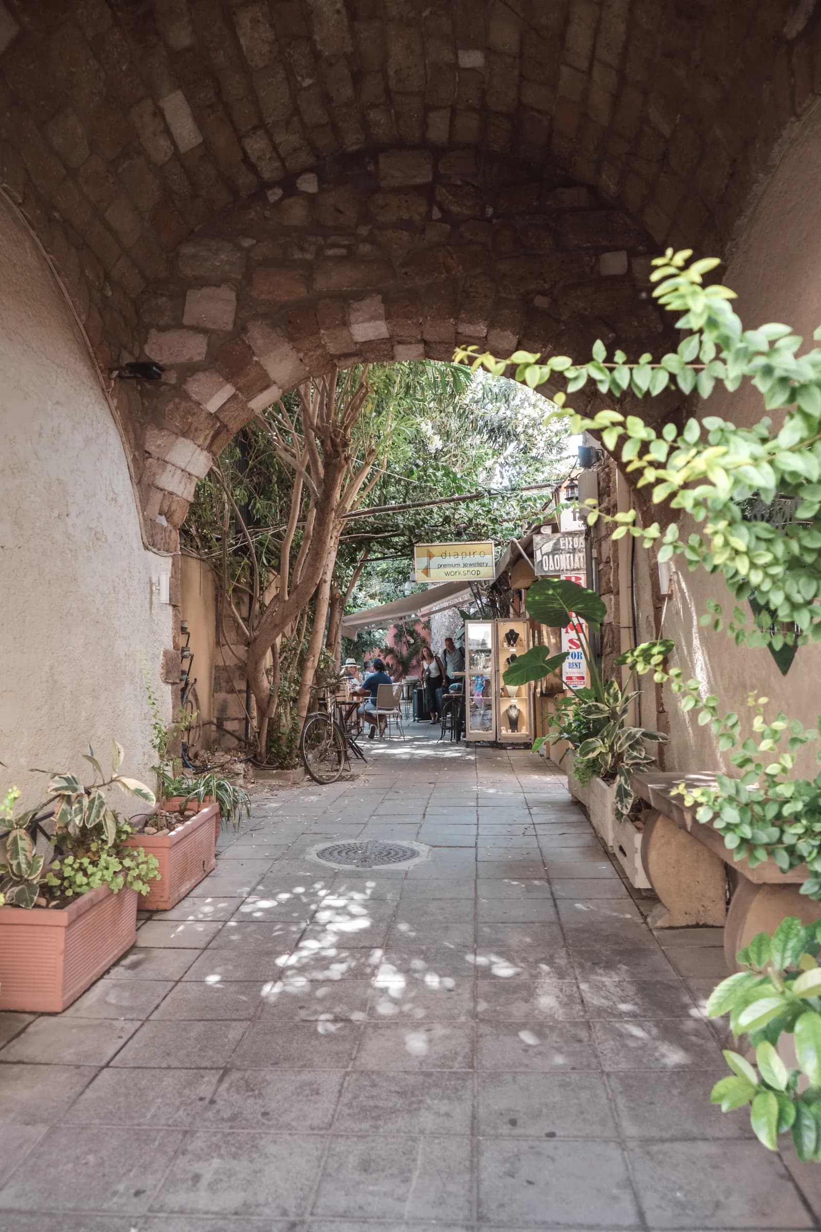Passage voûté en pierre ouvrant sur une ruelle ombragée de la vieille ville de La Canée