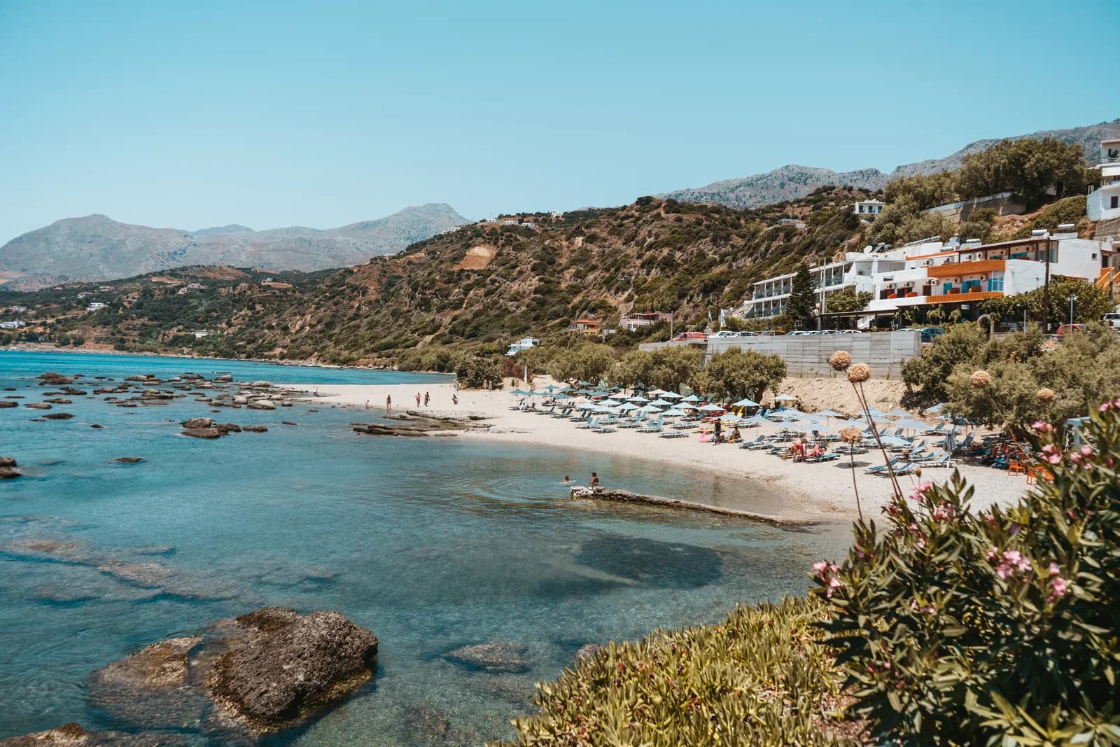 Crique aux eaux turquoises et rochers plats près de Plakias, avec ses transats et ses collines sur la côte sud