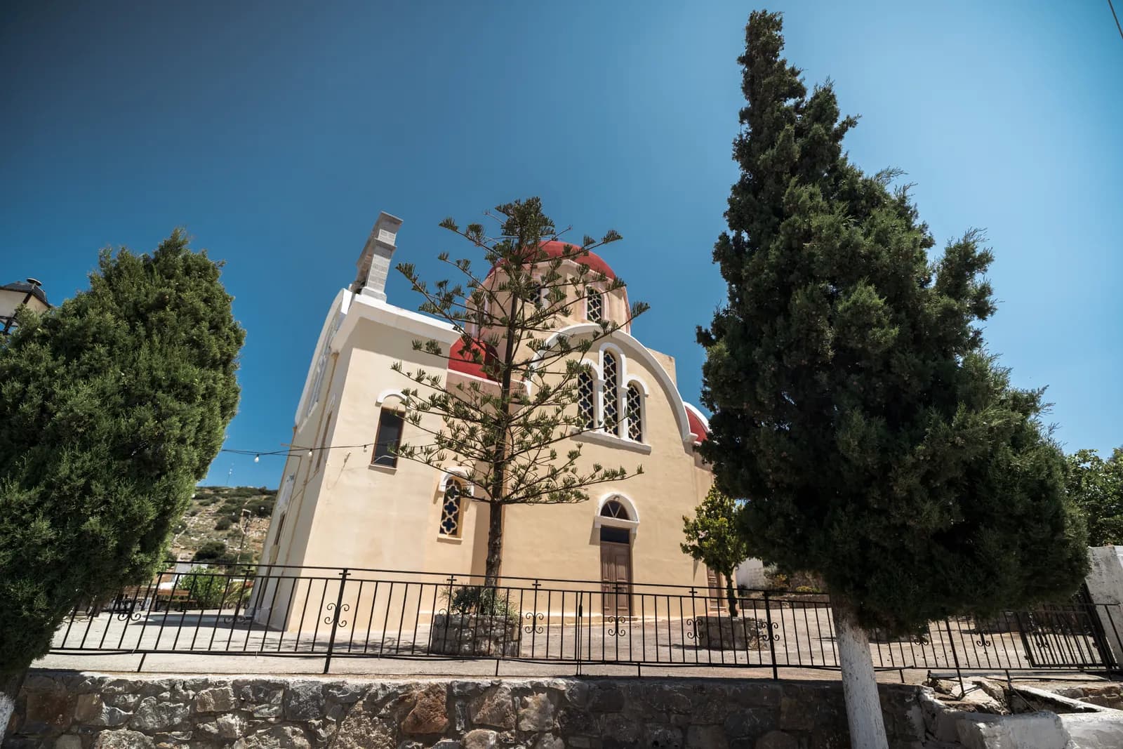 Église aux coupoles rouges entre les cyprès dans un village de l'arrière-pays au nord de Plaka