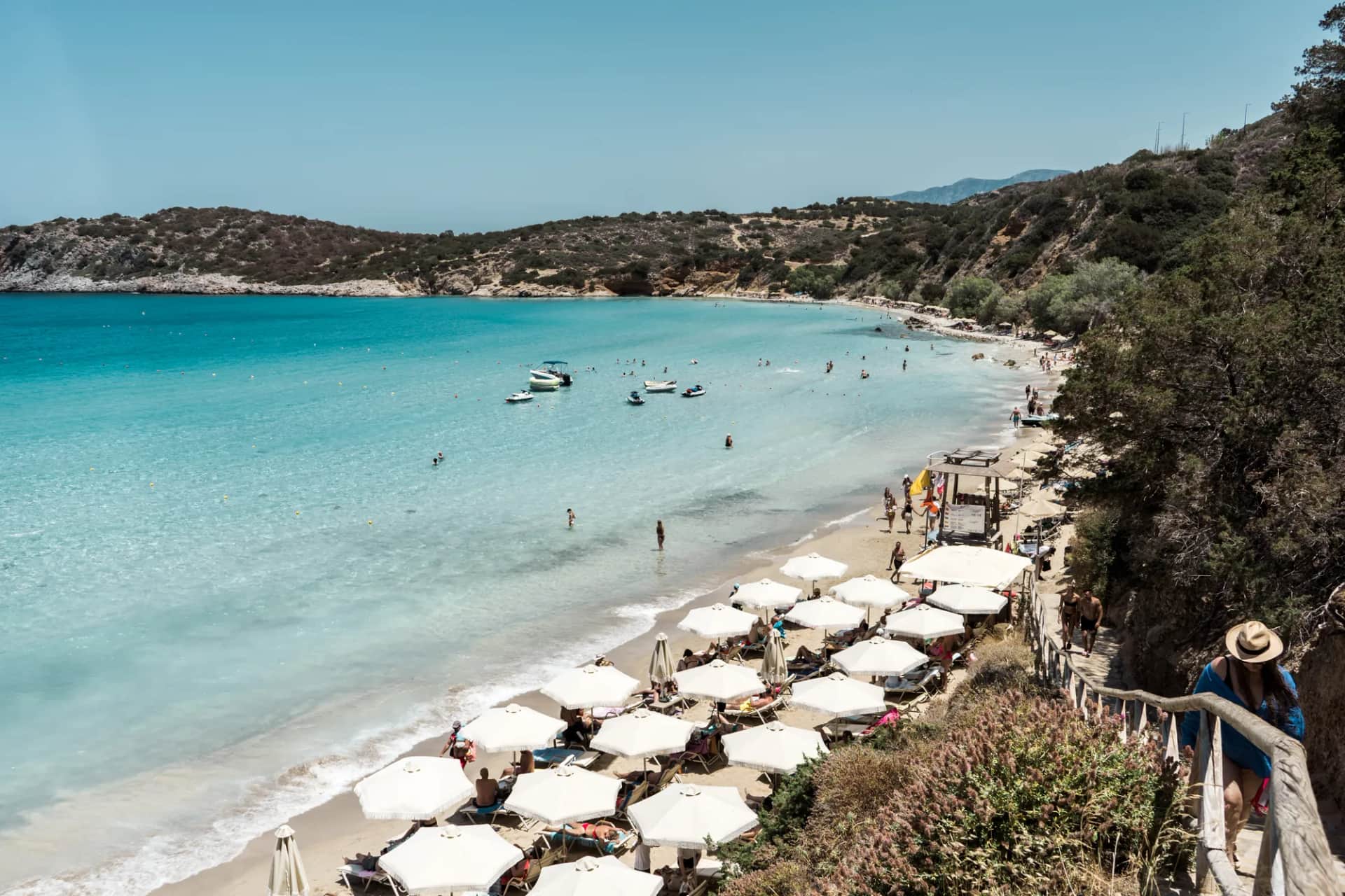 La plage de Voulisma à Istro vue du sentier d'accès, avec ses parasols blancs et son eau turquoise