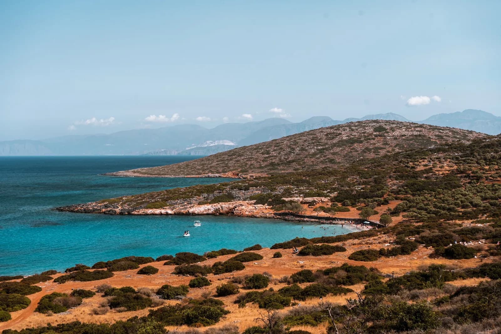 Crique turquoise bordée de garrigue et de terre rouge sur la côte du golfe près d'Elounda