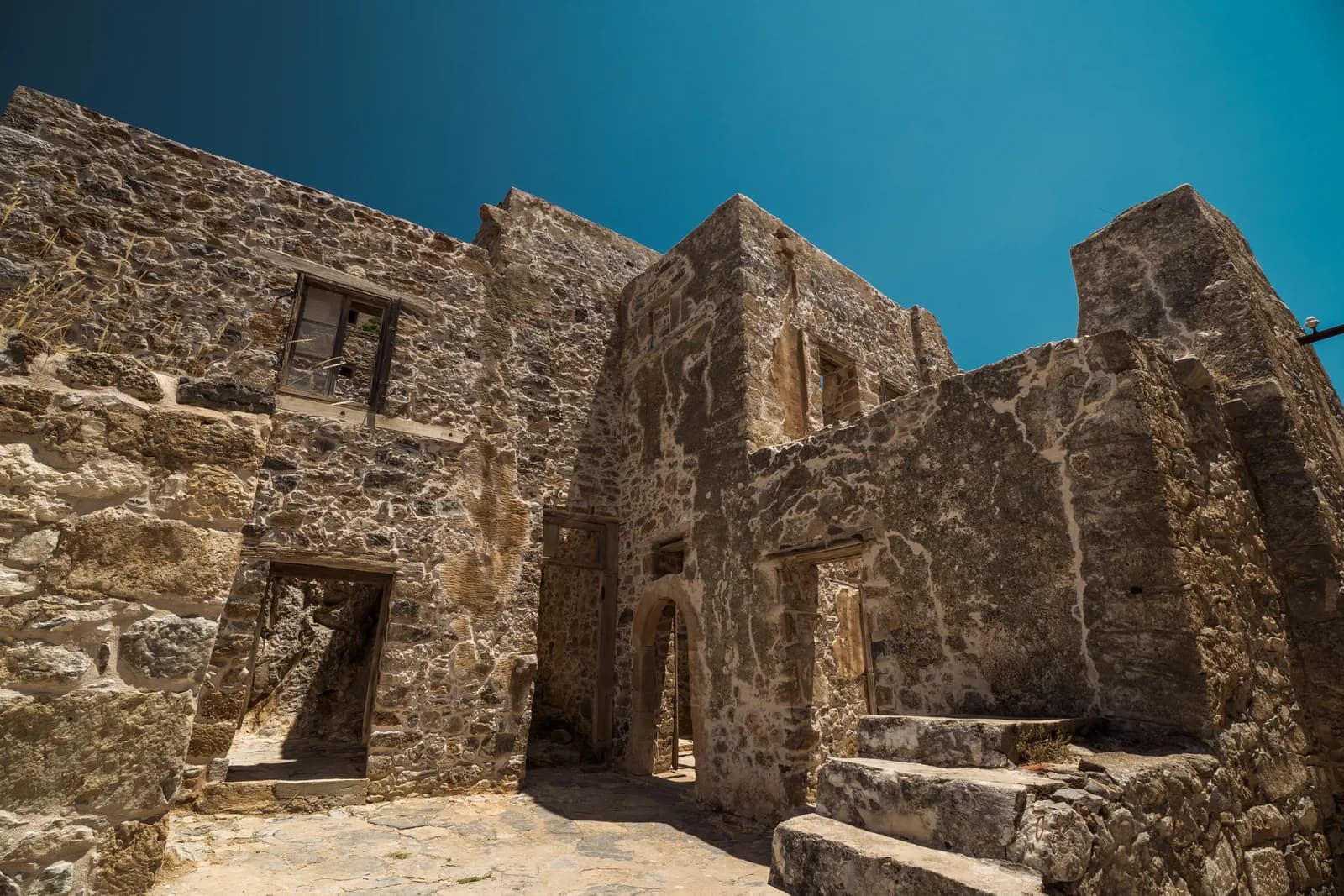 Maisons de pierre en ruine de l'ancienne léproserie de Spinalonga sous un ciel bleu profond