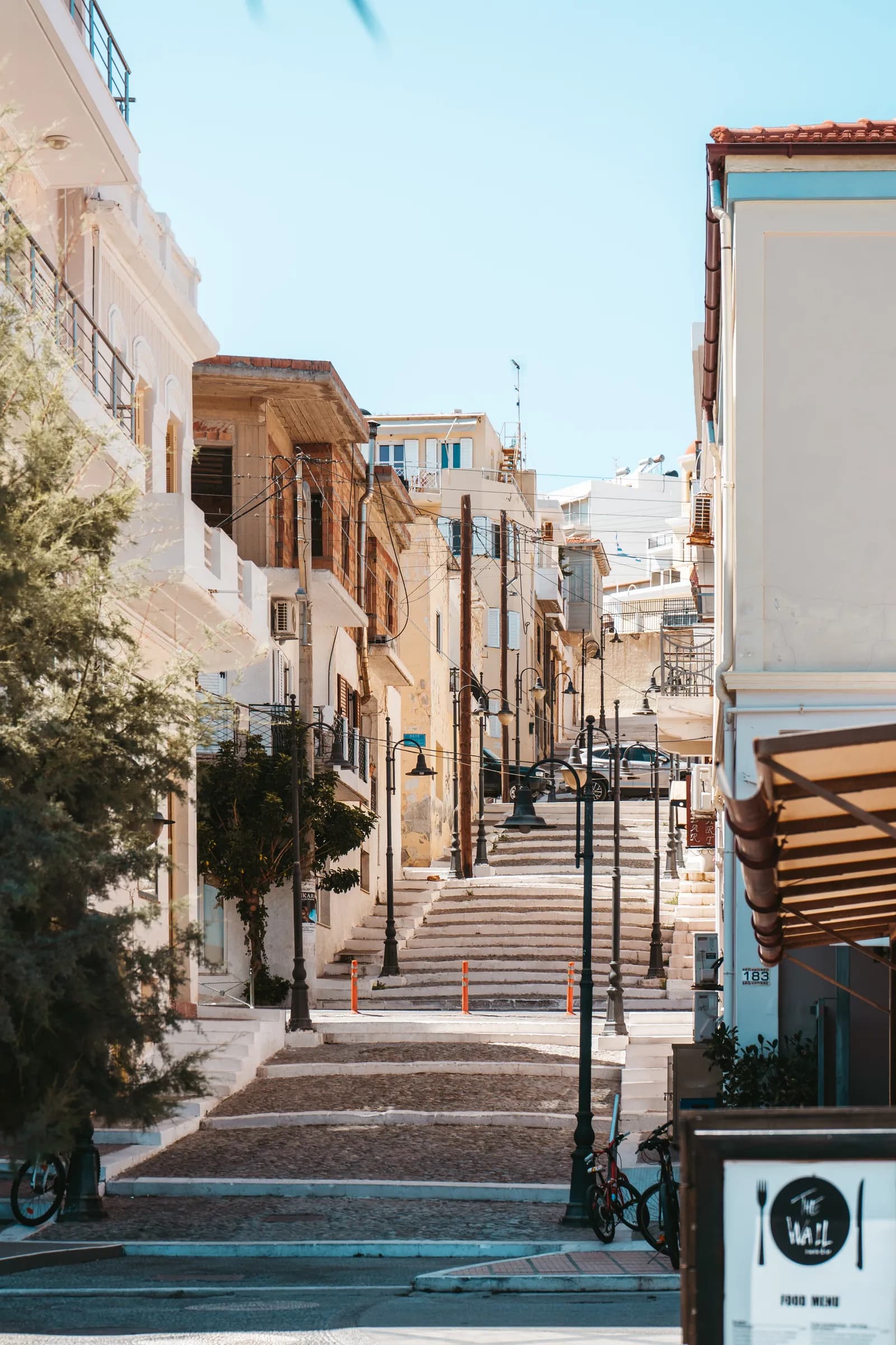 Escalier de rue bordé de réverbères et de maisons claires qui grimpe vers le haut de la ville de Sitia