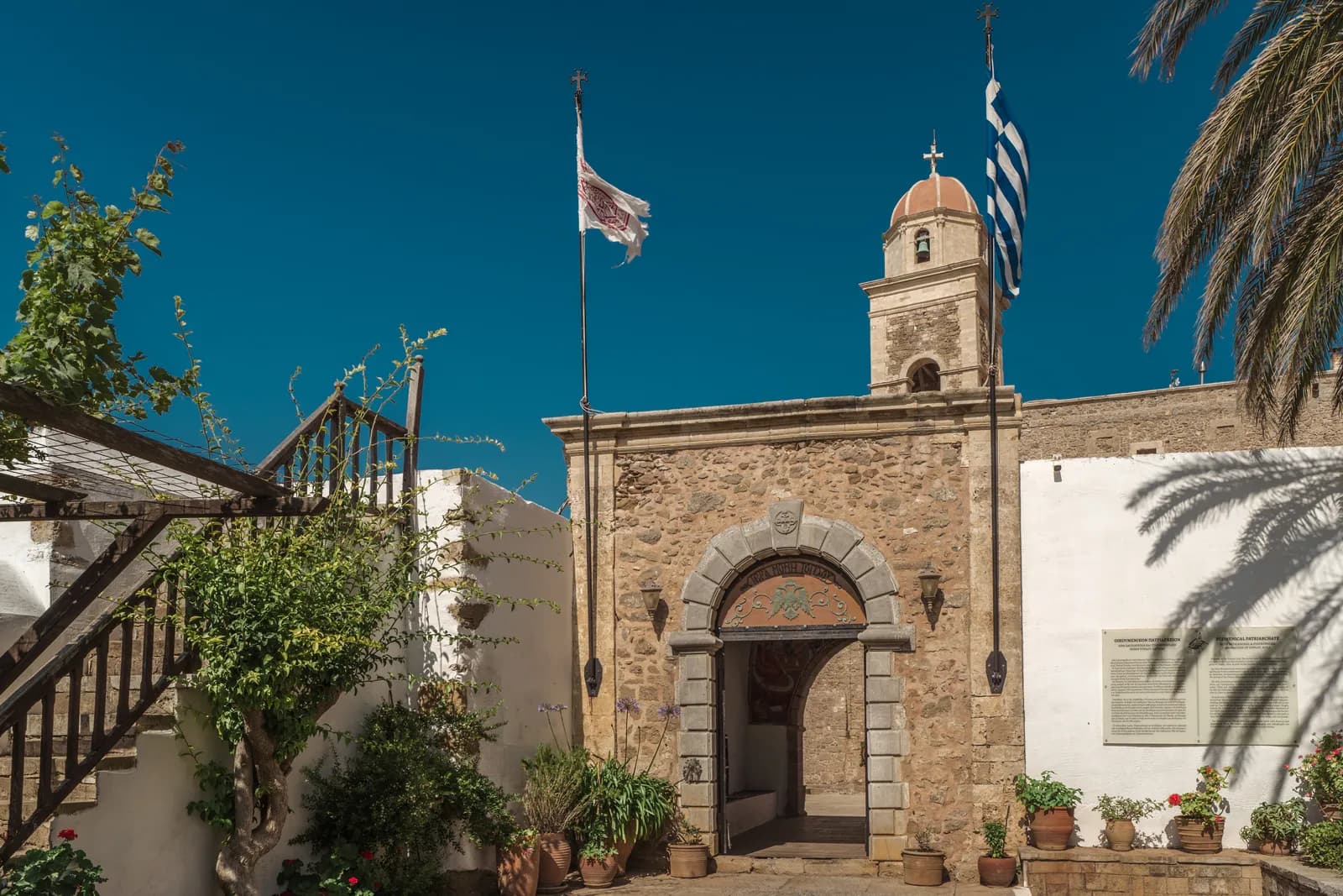 Le portail en pierre du monastère de Toplou, surmonté de son clocher et flanqué du drapeau grec