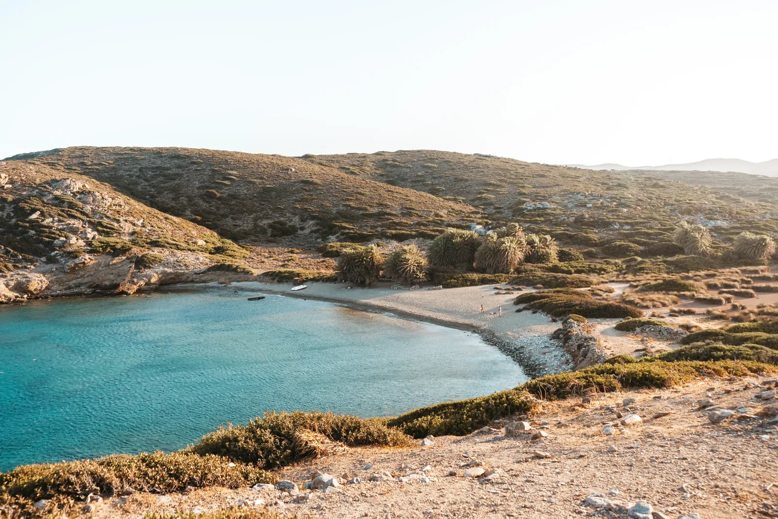 Crique de sable bordée de palmiers et de collines sèches sur la côte sauvage de l'extrême est de la Crète