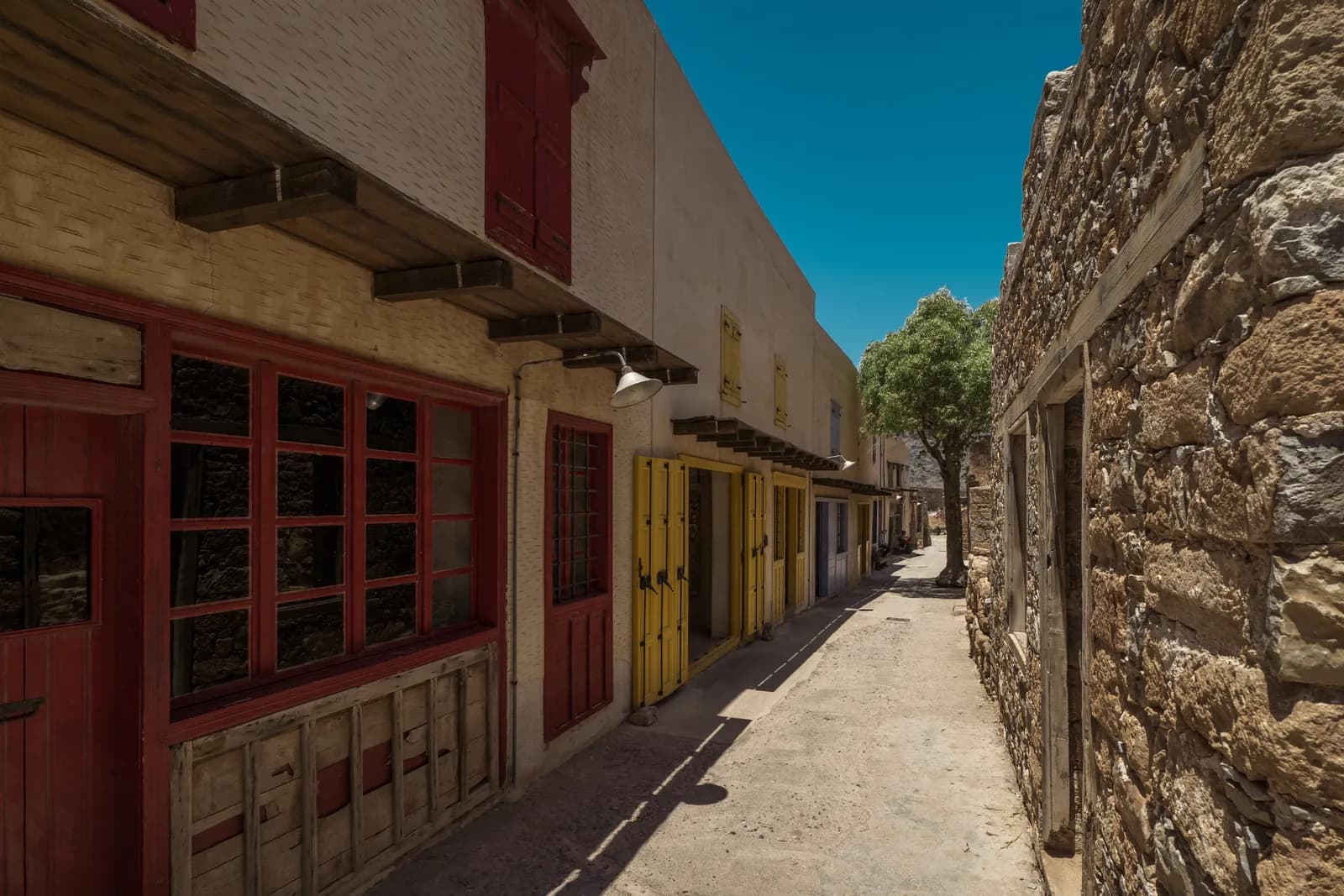 The restored main street of Spinalonga village, its red and yellow shutters facing the stone walls