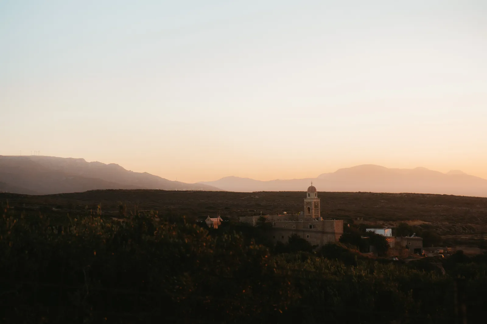 Le monastère fortifié de Toplou et son clocher au crépuscule, isolé sur le plateau face aux montagnes