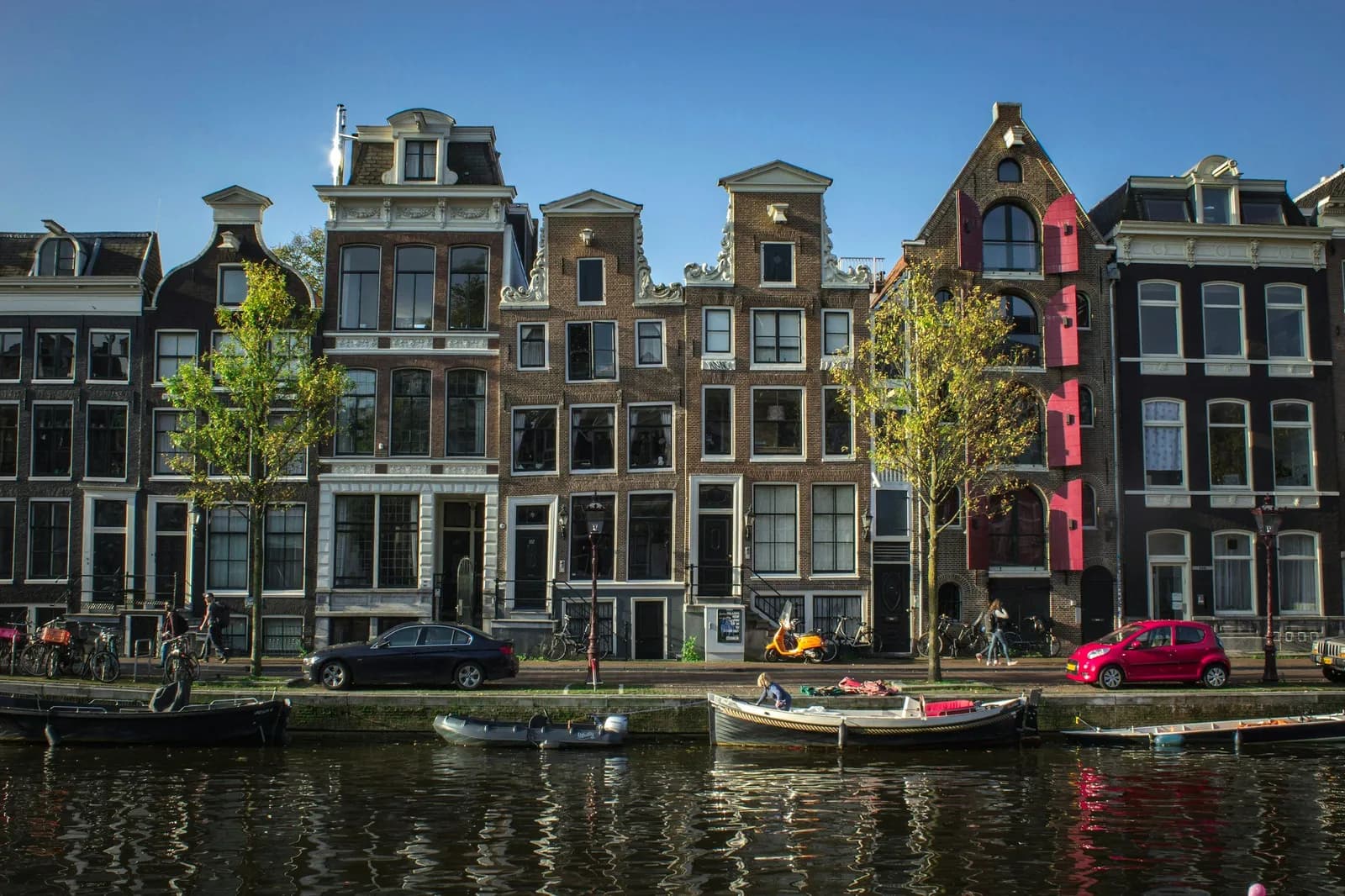 Rangée de hautes maisons de canal en brique à pignons sculptés le long d'un canal d'Amsterdam, par beau temps