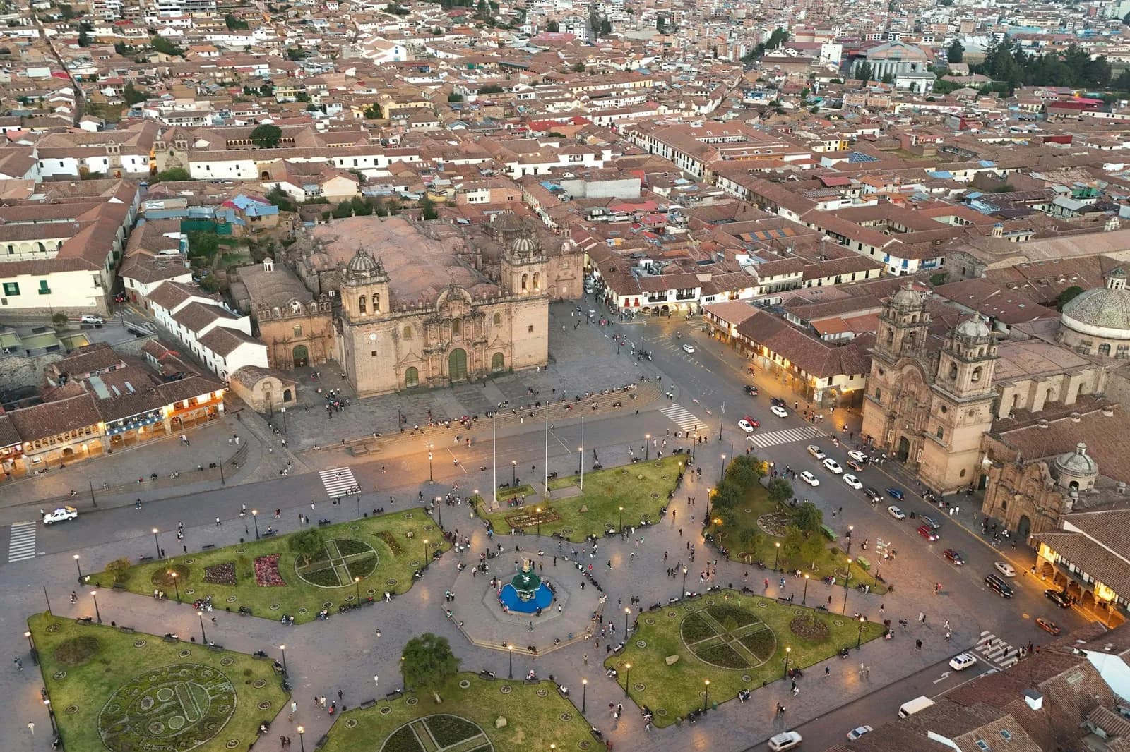 Aerial view of Cusco's Plaza de Armas at dusk, with the cathedral and the Compañía church