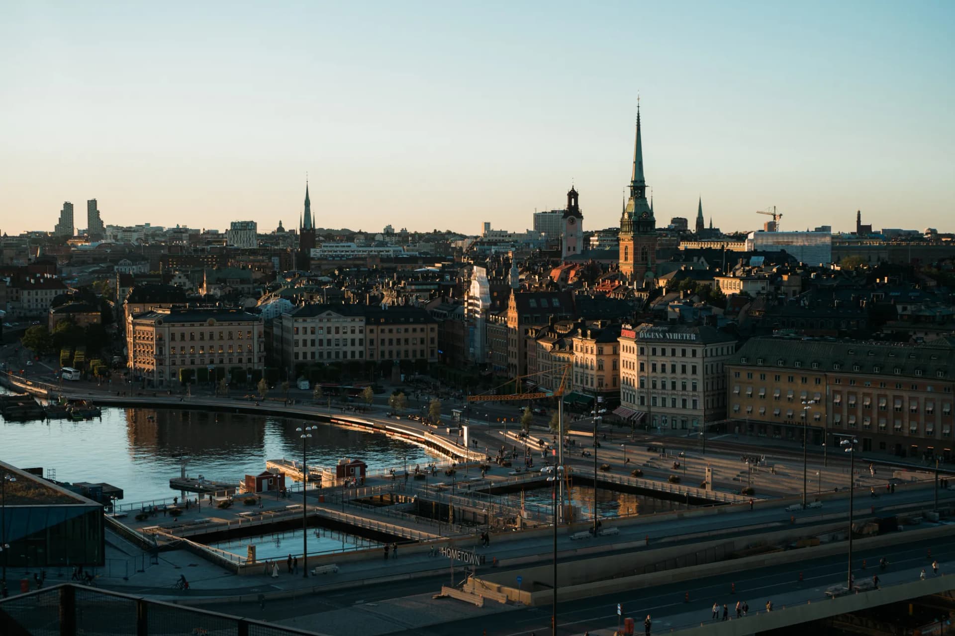 Vue en hauteur sur Gamla Stan dans la lumière dorée du soir, avec la flèche de l'église allemande au-dessus de Slussen