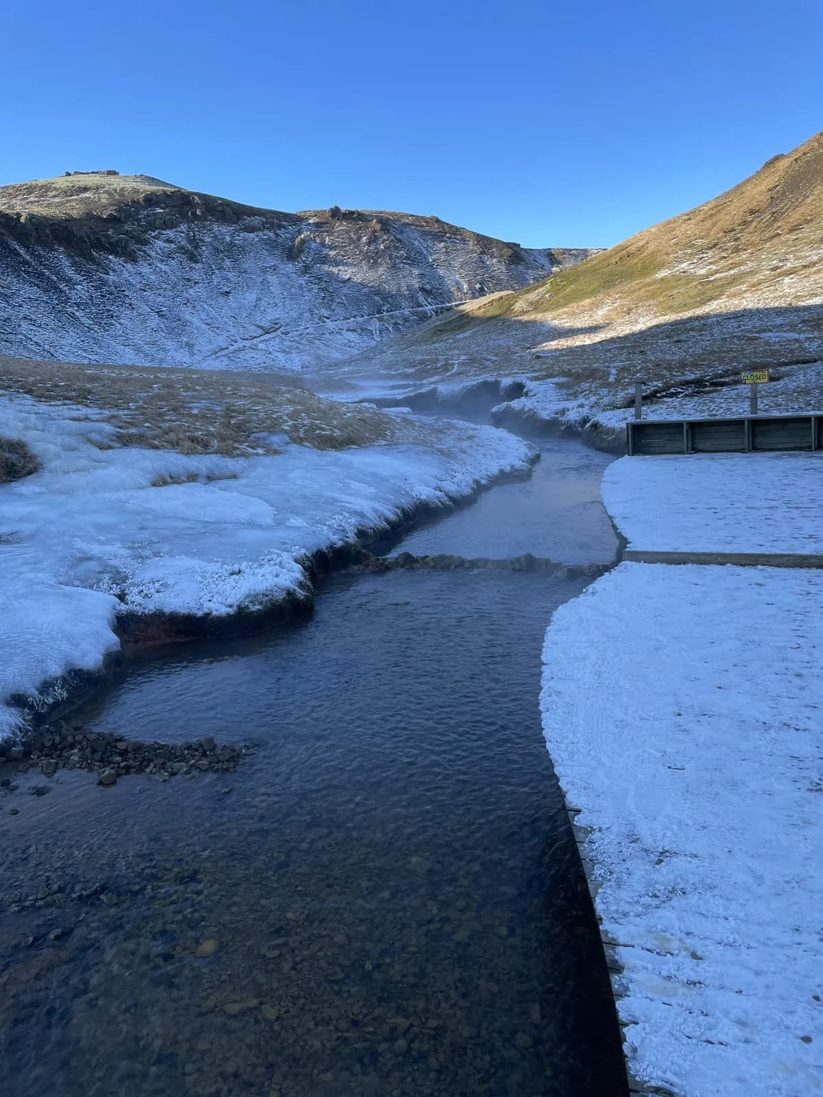la rivière chaude de Reykjadalur entre des rives enneigées, en février
