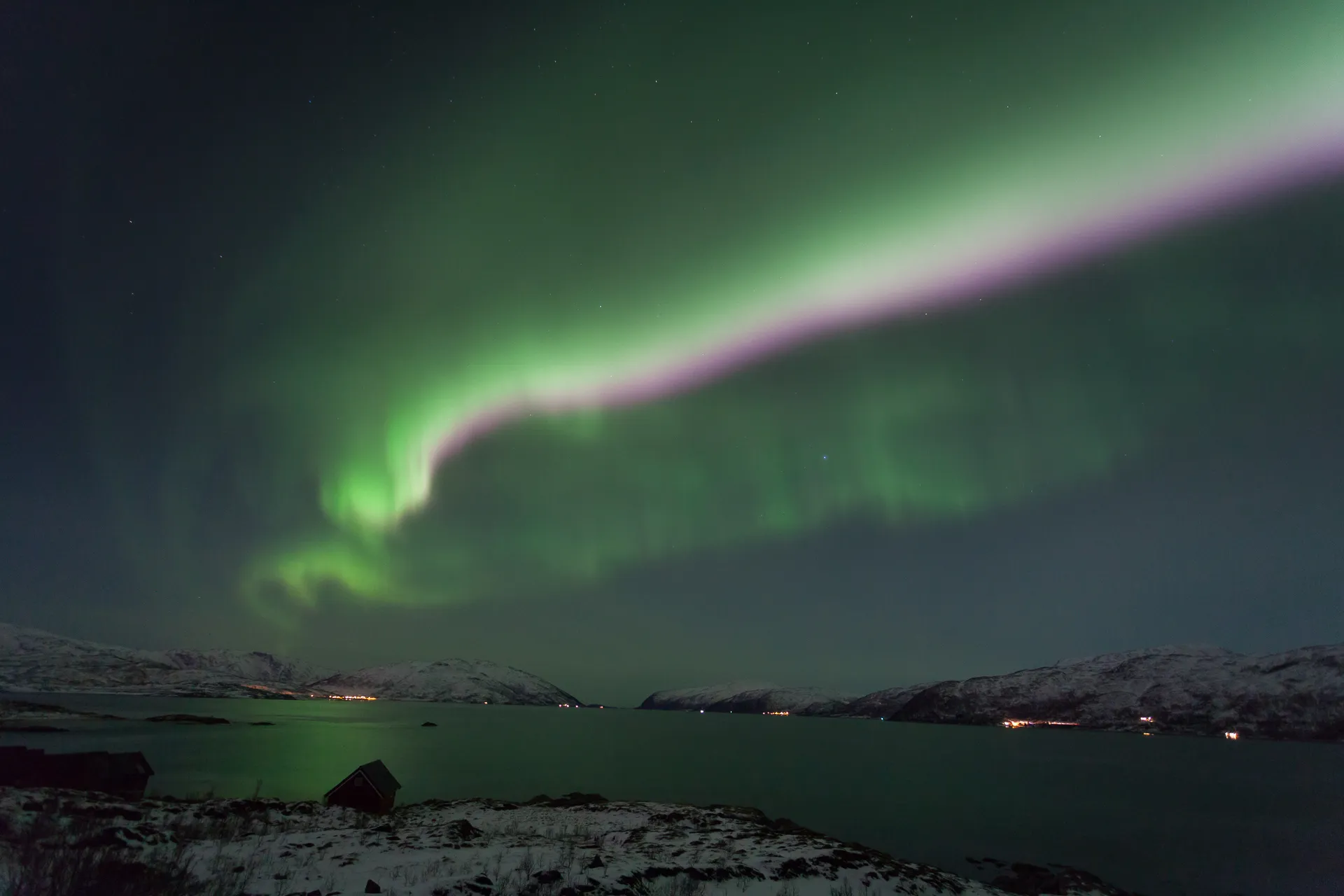 Aurore boréale verte et rose au-dessus d'un fjord de l'île de Kvaløya, près de Tromsø